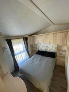 Ce lit se trouve dans une petite chambre dotée d'une fenêtre. dans l'établissement Willerby Granada 2-Bedroom Parkhome, Glasgow, à Uddingston