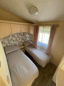 - une petite chambre avec 2 lits et une fenêtre dans l'établissement Willerby Granada 2-Bedroom Parkhome, Glasgow, à Uddingston