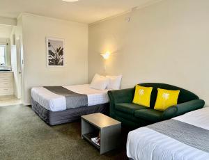 una habitación de hotel con 2 camas y un sofá verde en Parkside Motel and Apartments, en New Plymouth