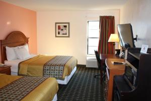 a hotel room with two beds and a desk and a television at Executive Inn and Suites Wichita Falls in Wichita Falls