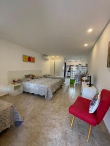 a bedroom with two beds and a red chair at Condomínio Oasis das Flores in Porto De Galinhas