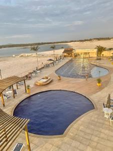 a large swimming pool next to a sandy beach at Arraial do Cabo - Condomínio com cara de Resort in Arraial do Cabo