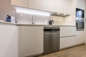 una cocina con armarios blancos y electrodomésticos de acero inoxidable en Homity Exclusive Playa Granada Beach & Golf - Mar de Astrid en Motril