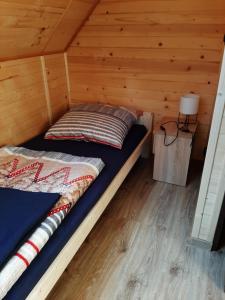 a bed in a cabin with a wooden wall at Czarny Potok Domki całoroczne in Czarna