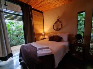 a bedroom with a bed and a large window at Casa jardim com ofurô - Chapada dos veadeiros in Cavalcante