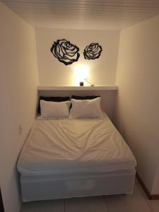 a white bed in a room with two signs on the wall at Lindo Flat em Maresias in São Sebastião