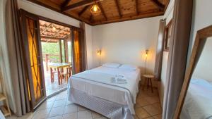 a bedroom with a bed and a balcony with a table at Nossa Guarda Acomodações in Guarda do Embaú
