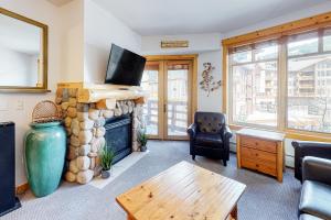 a living room with a stone fireplace and a table at Tucker Mountain Lodge 307a in Copper Mountain