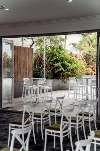 un gruppo di sedie e tavoli bianchi su un patio di Vali Byron a Byron Bay