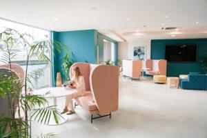 a woman sitting at a table in a waiting room at Vali Byron in Byron Bay