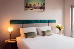 a bedroom with a white bed with a green headboard at Vali Byron in Byron Bay