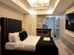 een slaapkamer met een groot bed en een televisie bij Elegant Studio with videoke at Azure North Pampanga in San Fernando