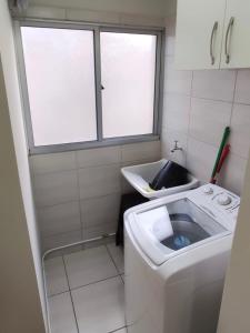 baño pequeño con lavadora y ventana en Aconchego Poços de Caldas, en Poços de Caldas