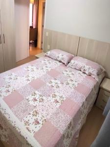 a bed with a pink and white quilt on it at Aconchego Poços de Caldas in Poços de Caldas