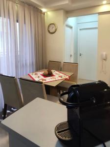 ein Zimmer mit einem Tisch und Stühlen sowie einer Uhr an der Wand in der Unterkunft Aconchego Poços de Caldas in Poços de Caldas