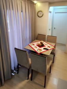 a dining room table with chairs and a clock on the wall at Aconchego Poços de Caldas in Poços de Caldas