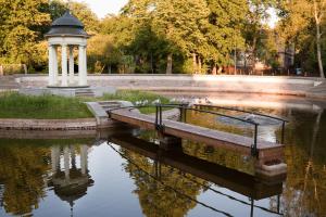 a pond with a gazebo and birds in a park at Uliha Apartamenti in Liepāja