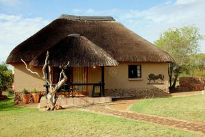 Una cabaña con techo de hierba con un caballo. en Ukutula Lion Lodge, en Brits