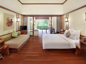 a bedroom with a large bed and a living room at Novotel Bogor Golf Resort in Bogor