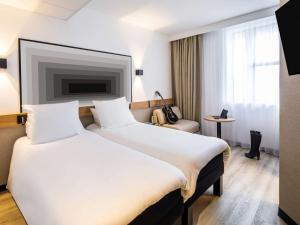 ibis Brest Centre في بريست: غرفة فندقية بسرير كبير وكرسي