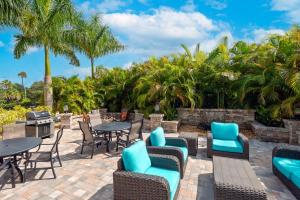 eine Terrasse mit Tischen und Stühlen sowie einem Grill und Palmen in der Unterkunft Ameniti Bay - Best Western Signature Collection in Sarasota