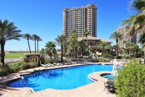 a swimming pool with palm trees and a tall building at Portofino Island Resort & Spa 1-2003 in Pensacola Beach