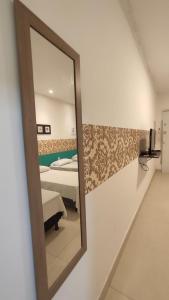 einen Spiegel an der Wand in einem Zimmer mit Betten in der Unterkunft Angel Hospedagem de quartos in Vila Velha