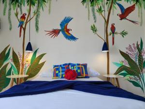a bedroom with a bed with birds and trees on the wall at Pousada Costa Del Sol in Búzios