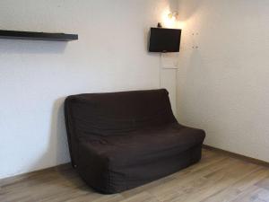 uma cadeira castanha sentada num canto de uma sala em Appartement Vars, 1 pièce, 2 personnes - FR-1-330B-119 em Vars