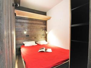 um quarto com uma cama vermelha com um livro em Appartement Saint-Chaffrey , 2 pièces, 6 personnes - FR-1-330E-109 em Saint-Chaffrey