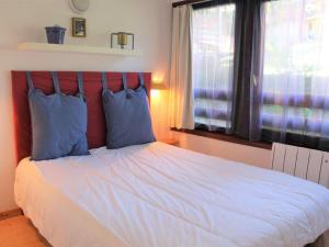 瓦爾的住宿－Appartement Vars, 2 pièces, 4 personnes - FR-1-330B-129，一间卧室配有一张带蓝色枕头的床和一扇窗户。