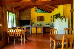 a kitchen with a white refrigerator and wooden tables at Posada Camboatá in Aristóbulo del Valle