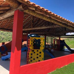 a playground under a roof with a play structure at Rancho das Montanhas in Muniz Freire