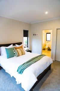 - une chambre avec un grand lit blanc et des oreillers colorés dans l'établissement Eildon 138, à Eildon