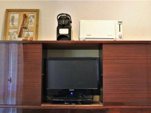 a television on a wooden shelf with a phone and a box at Appartement Risoul, 1 pièce, 4 personnes - FR-1-330-498 in Risoul