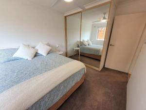 een slaapkamer met een groot bed en een spiegel bij Ocean Front Apartment in Cronulla