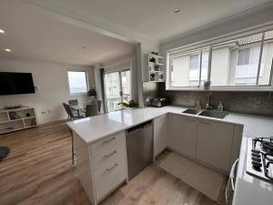 una cocina con encimeras blancas y una cocina con ventanas en Ocean Front Apartment, en Cronulla