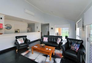 a living room with black leather chairs and a coffee table at 46 Holland Street Bargara in Bargara