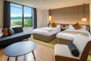 a hotel room with two beds and a couch at KAMENOI HOTEL Ome in Ome