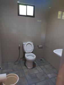 a bathroom with a toilet and a sink and a window at MilVir Tourist INN in El Nido