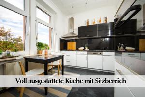 une cuisine avec des placards blancs et une table noire dans l'établissement 80m2 3R Wohnung mit privatem Parkplatz, Kingsize Betten, Smart-TV, etc, à Erfurt