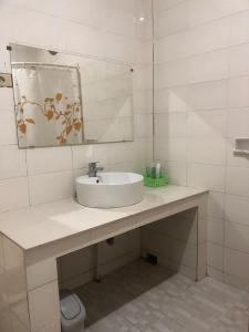 a white bathroom with a sink and a mirror at Hotel Monika in Rantepao