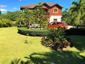 un'auto arancione parcheggiata di fronte a una casa di Villa Amila By Hospedify Hermosa Villa para 20 personas y a 4 minutos del Río de Jarabacoa a Jarabacoa