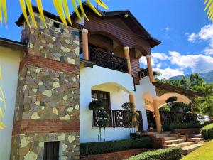 una casa con un muro in pietra e un balcone di Villa Amila By Hospedify Hermosa Villa para 20 personas y a 4 minutos del Río de Jarabacoa a Jarabacoa