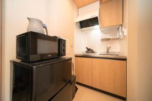 a kitchen with a microwave on top of a refrigerator at WELLSTAY Shinsekai Wakyo in Osaka