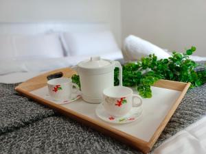 uma bandeja com duas chávenas e um conjunto de chá numa cama em KLIA EHSAN Residence Sepang Nilai Greenery 8 PAX Air-Con Suite em Sepang