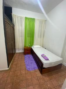 a small bedroom with a bed and a green window at La casa de Isabel y Juan, Zona Colonial in Santo Domingo