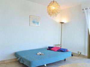een slaapkamer met een blauw bed en een kroonluchter bij Appartement Le Lavandou, 2 pièces, 4 personnes - FR-1-251-287 in Le Lavandou