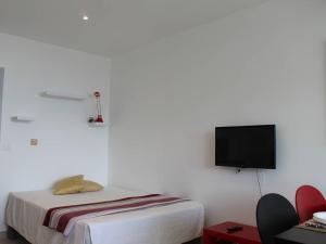 Cette chambre blanche dispose d'un lit et d'une télévision à écran plat. dans l'établissement Appartement Villeneuve-Loubet, 1 pièce, 2 personnes - FR-1-252A-19, à Villeneuve-Loubet