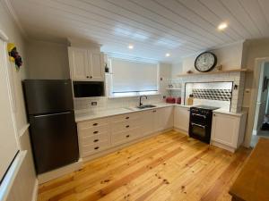 eine Küche mit einem schwarzen Kühlschrank und einer Uhr an der Wand in der Unterkunft Glendale Cottage in Daylesford